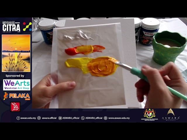 An artist's workspace with an acrylic painting, dream catcher materials, and paper cutting tools arranged on a wooden table